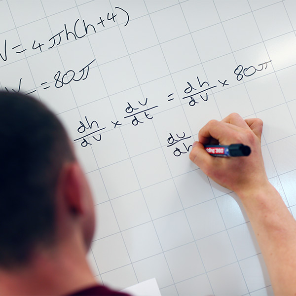 Maths student using whiteboard to write equations